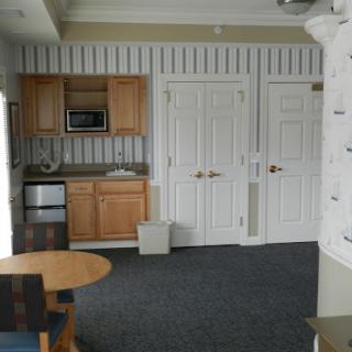 A cozy kitchenette area featuring wooden cabinets, a small dining table, and essential appliances.