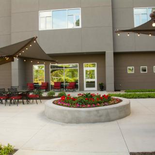 A modern outdoor patio with seating and string lights next to a building.