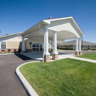A building entrance with a covered canopy and surrounding landscaped lawn.
