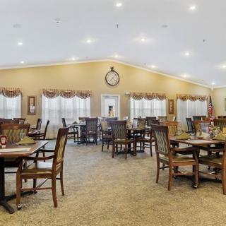 Spacious dining room with neatly arranged tables and chairs, featuring warm lighting and large windows.