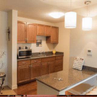 A modern kitchen with wood cabinets, a microwave, and pendant lights.