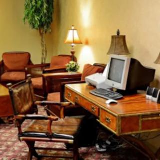 A vintage office setup with a wooden desk and an old computer, surrounded by comfortable chairs and warm lighting.