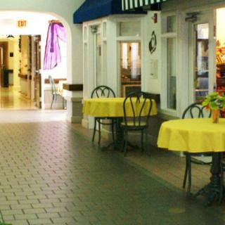 Outdoor cafe area with yellow tablecloth-covered tables and chairs along a paved walkway.