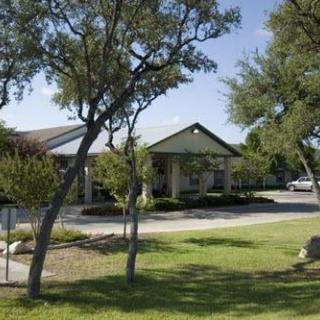 A sunny day with a view of a building surrounded by trees and a well-maintained lawn.