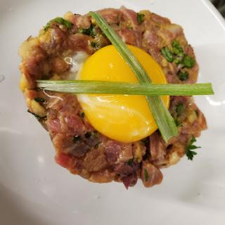 A beautifully presented dish of tartare topped with a fresh egg yolk and green onions.
