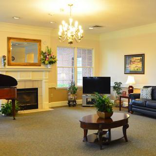 A cozy living room with elegant decor, featuring a chandelier, fireplace, and comfortable seating.