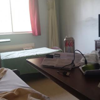A view of a hospital room featuring a bed, a table with drinks and food, and a television.