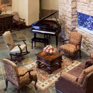A cozy living room with a grand piano and comfortable seating around a coffee table.