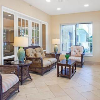 A cozy living room with comfortable seating, tables, and large windows providing natural light.