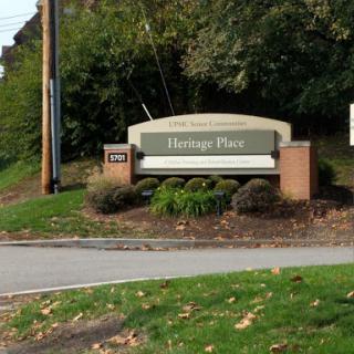 Entrance sign for Heritage Place surrounded by lush greenery.