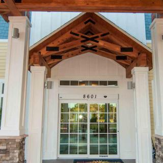 A building entrance featuring a wooden porch and glass doors.