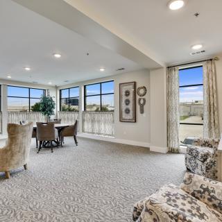 A spacious and elegantly designed living room with a dining area, featuring large windows that allow plenty of natural light.