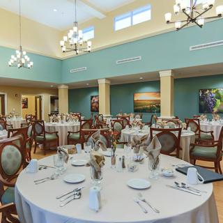 An elegant dining room with neatly arranged tables and chairs, featuring chandeliers and tasteful decor.