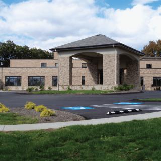 A modern building with a covered entrance and adjacent parking lot.