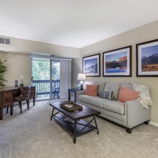 A cozy living room with a sofa, coffee table, and dining area, decorated with wall art.