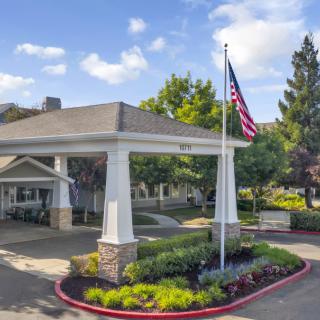 An entrance area with a flagpole and landscaped surroundings on a sunny day.