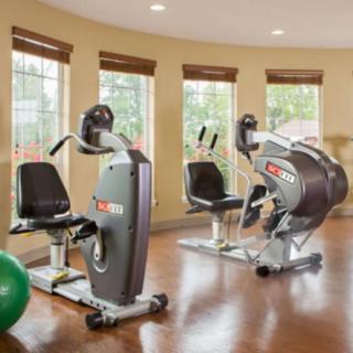 A well-lit gym room with stationary bikes and an exercise ball.