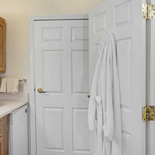 A bathroom with a white robe hanging on the door.