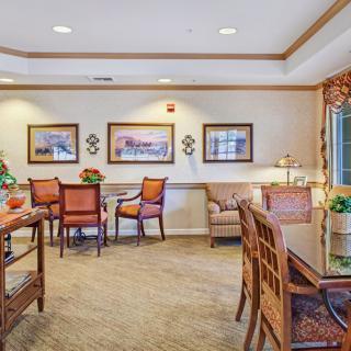 A cozy dining area with tables and chairs, decorated with framed art and warm lighting.