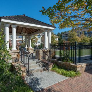 A charming gazebo surrounded by greenery under a clear blue sky.