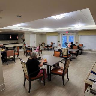 A cozy dining area with several tables and chairs, occupied by people enjoying their time.