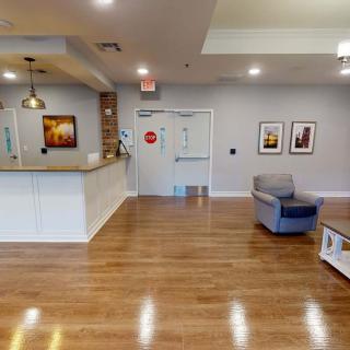 A modern lobby area featuring a reception desk, comfortable seating, and wooden flooring.