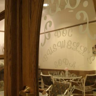 View through a wooden door into a cozy cafe with frosted glass decor.
