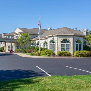 A well-maintained building with a parking lot, surrounded by trees under a clear blue sky.