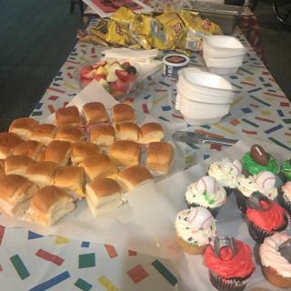 A party table set with sandwiches, cupcakes, and snacks.