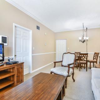 A cozy living room with a television, wooden furniture, and a dining area featuring a chandelier.