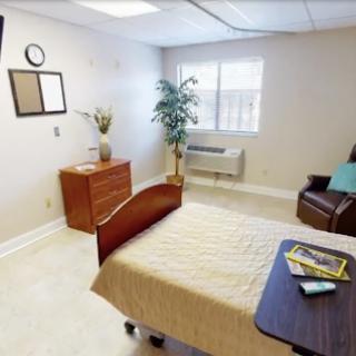 A well-lit and organized bedroom featuring a bed, dresser, and cozy seating area.