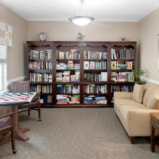 A cozy library nook with a large bookshelf, comfortable sofa, and a table with chairs.
