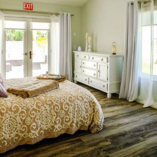 A cozy bedroom with elegant decor, featuring a bed with patterned bedding and large windows draped with curtains.