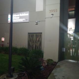 A view of a building's exterior at night, featuring a sign and surrounding greenery.