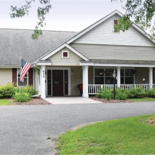 A suburban residential house with a front porch and an American flag displayed.