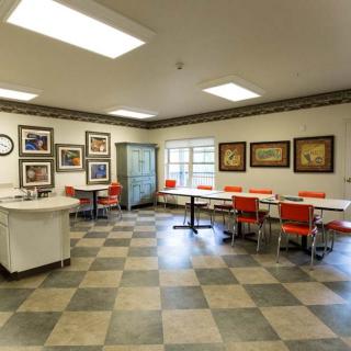 A cafeteria with red chairs, white tables, and artwork adorning the walls.