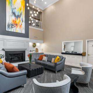 A modern living room with colorful artwork, comfortable seating, and stylish pendant lighting.