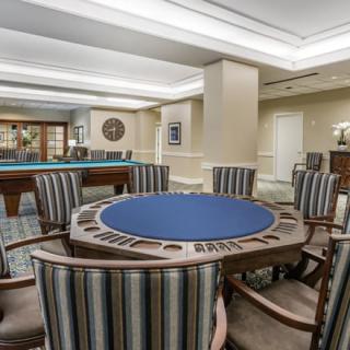 A stylish game room featuring a poker table and a pool table, with comfortable seating and elegant interior design.