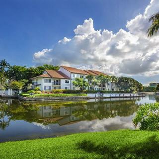 A picturesque house by the lake with clear reflections under a partly cloudy sky.