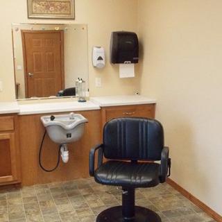A hair salon interior featuring a barber chair, sink, and mirror.