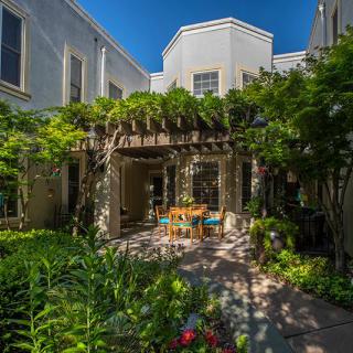 A tranquil courtyard garden with a pergola and outdoor seating surrounded by lush greenery.