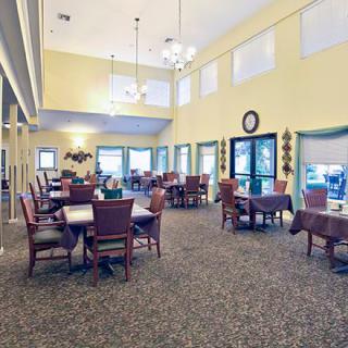 A spacious dining area with tables and chairs, featuring large windows and elegant lighting.