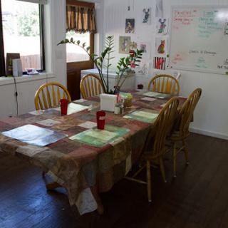 A cozy dining area with a wooden table, chairs, and indoor plants, perfect for casual meals.