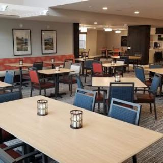 A spacious and modern dining area featuring neatly arranged tables and chairs, illuminated by soft lighting.