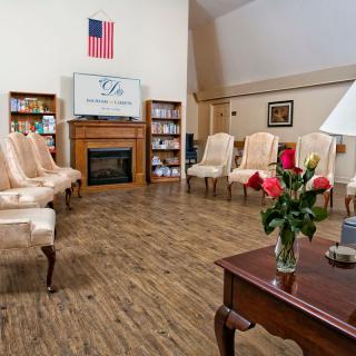 A cozy living room with ample seating and a fireplace, adorned with an American flag and fresh flowers.