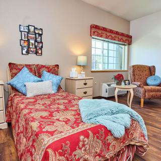 A cozy bedroom with a red-patterned bedspread, light blue pillows, and warm decor accents.