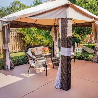 A cozy outdoor gazebo with comfortable seating in a backyard setting.