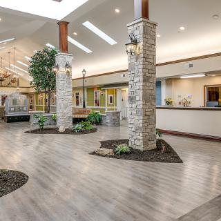 A spacious, modern lobby featuring stone pillars and indoor plants.