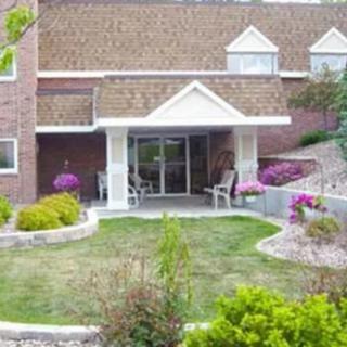 A landscaped garden in front of a building entrance with flowering plants and shrubs.
