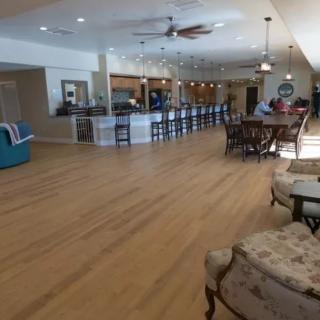 Spacious living room with wood flooring, featuring a dining area and a bar.